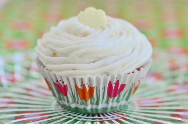 "Mini lemon cupcake in a pink and orange tulip lined paper on a glass plate"